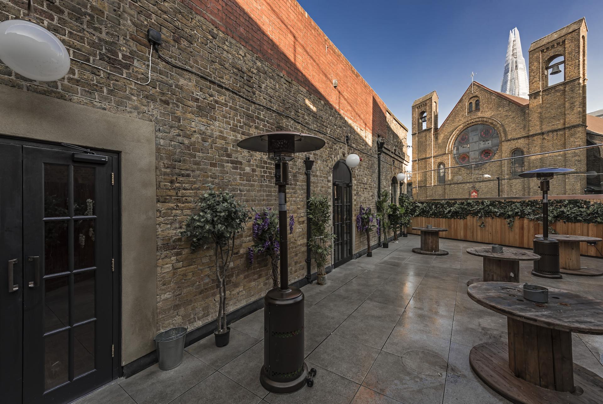 Urban outdoor space designed by align, featuring plants, tables, and historic architecture in the background.