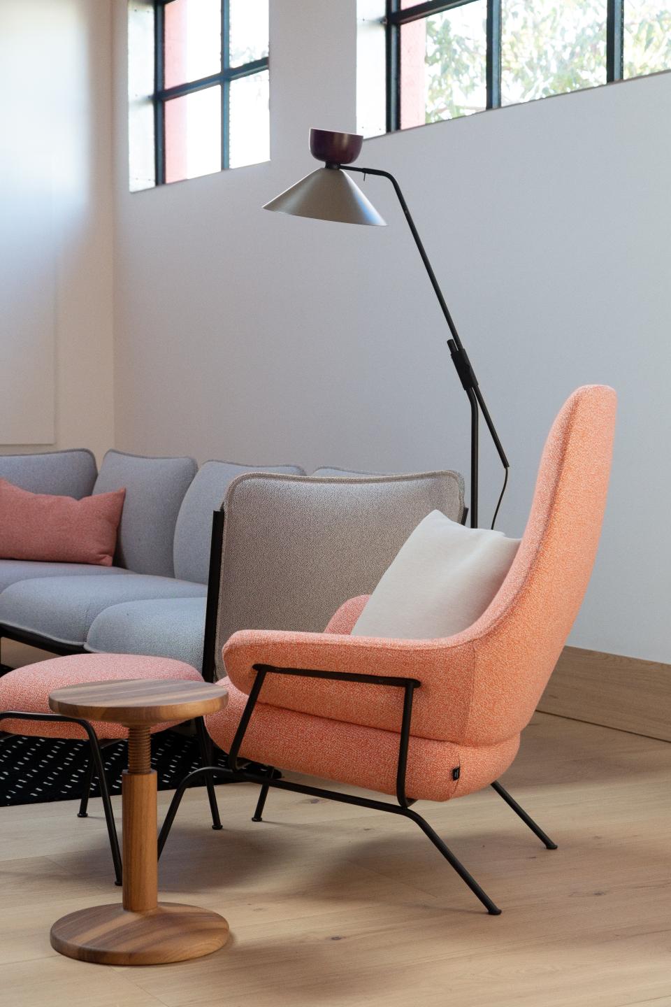 Contemporary Hem furniture showcased in a US showroom, featuring an orange accent chair and stylish wooden side table.