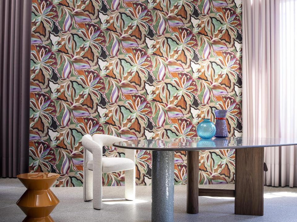 Modern interior featuring Arte's Tangram-inspired wallpaper, a round table, stylish chairs, and colorful decor elements.