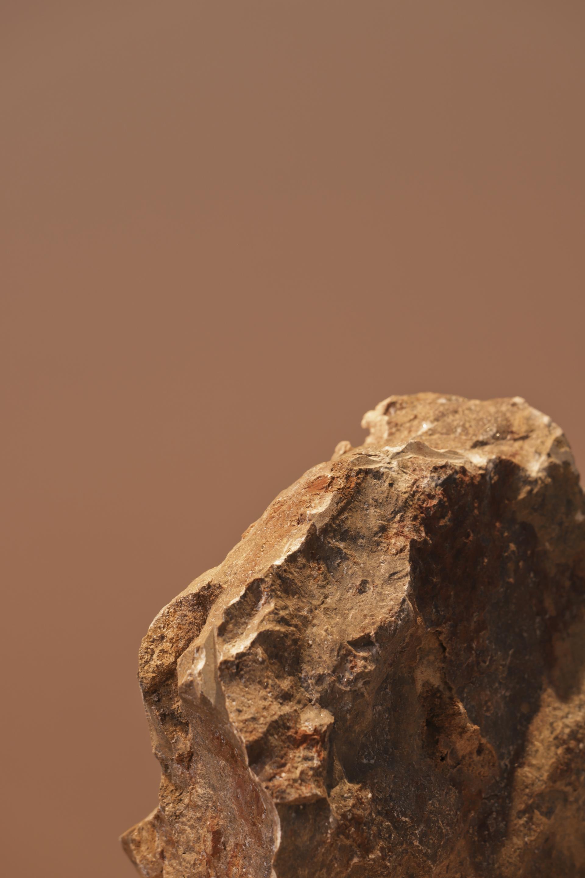 Textured rock formation against a warm, neutral background, showcasing the natural beauty of materials in the Meta collection.