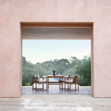 Bodil Kjær's architectural furniture set elegantly displayed in a serene outdoor setting with lush greenery.