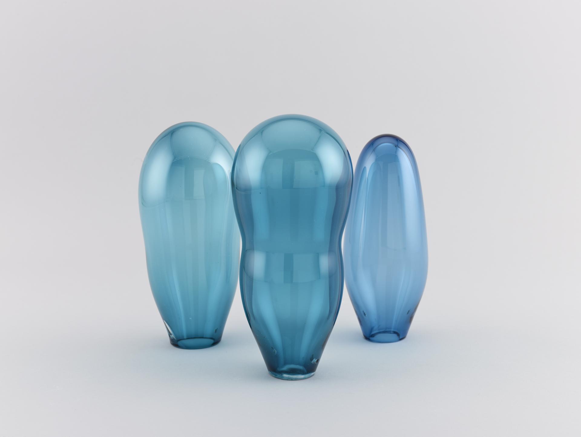Three elegant, translucent blue glass vases showcasing modern craftsmanship from the Midlands' post-industrial artistic revival.