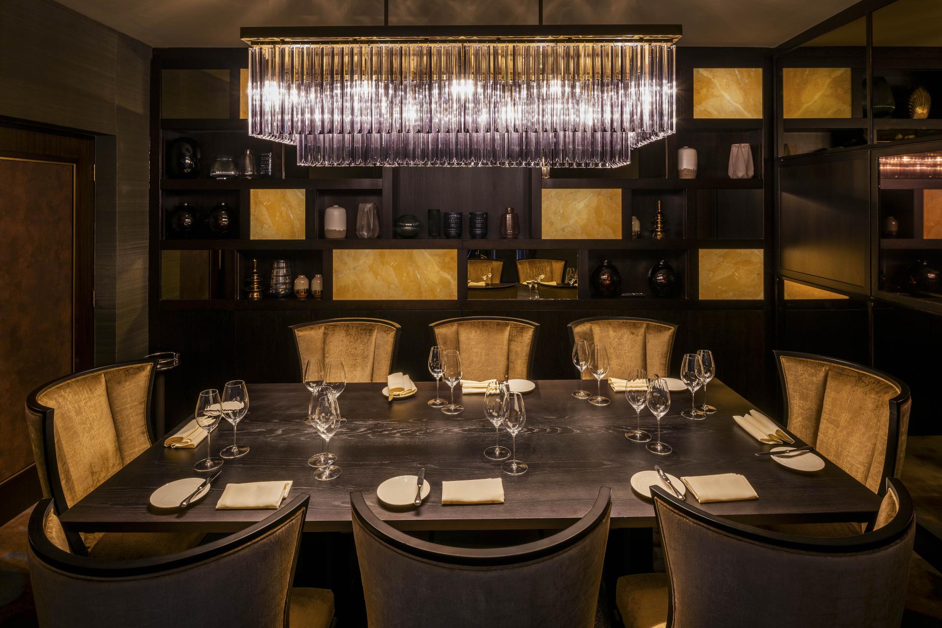 Elegant dining table set for guests, featuring luxurious chairs and a striking chandelier, highlighting Hollywood glamour at The Colony Club.