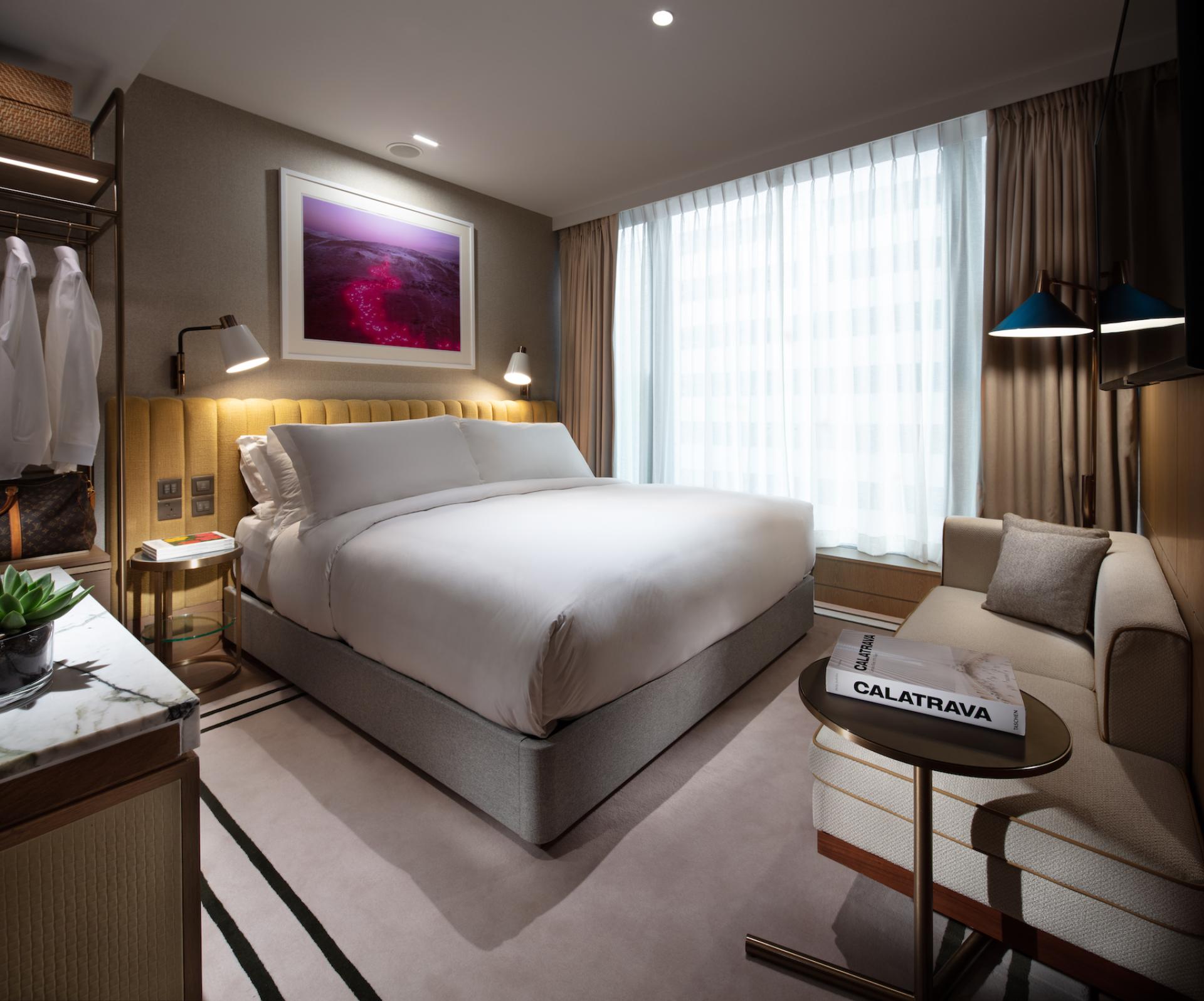 Stylish hotel room at The Hari Hong Kong featuring a queen-sized bed, modern decor, and large windows offering natural light.