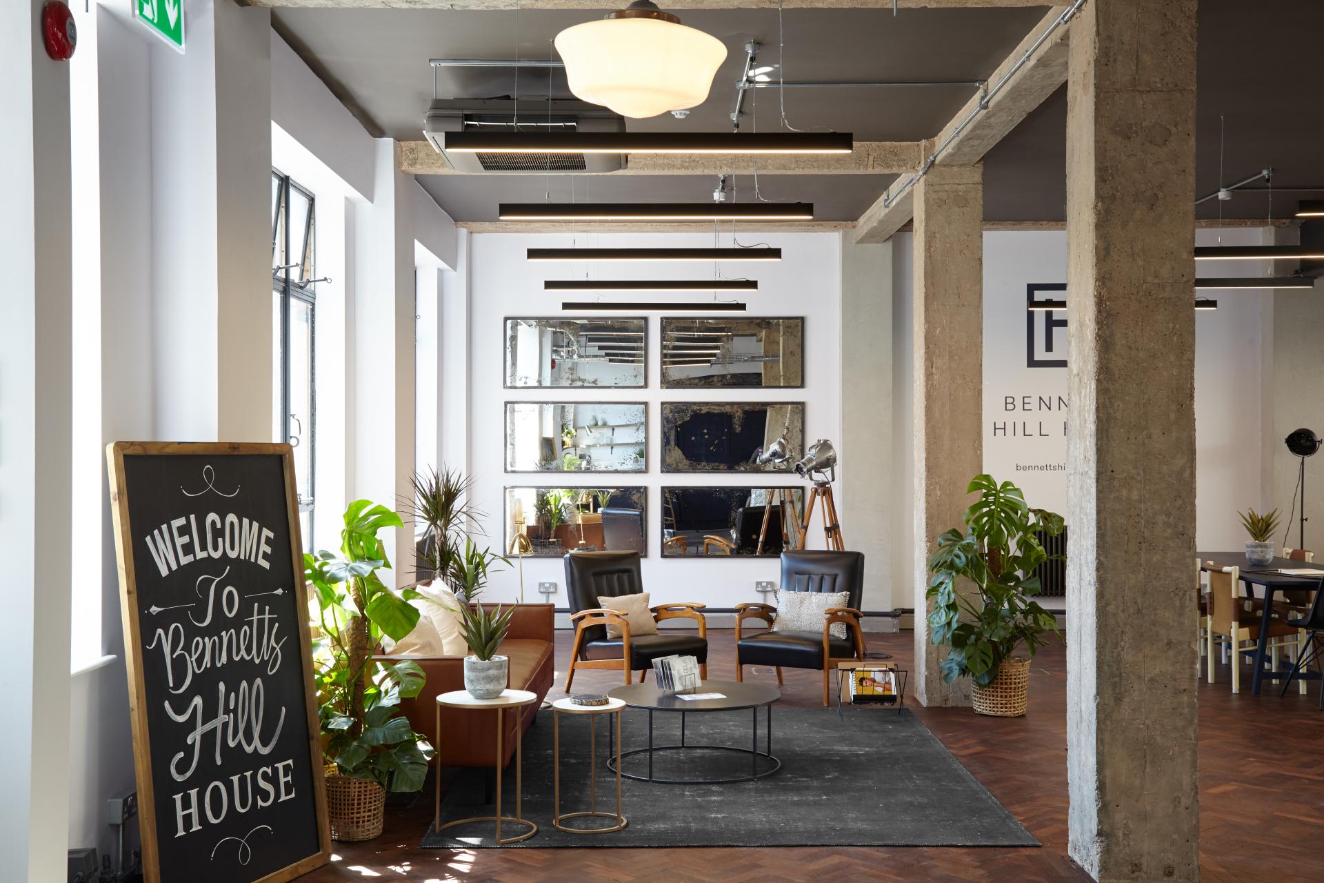 Chic loft-style office space featuring modern furnishings, plants, and decorative mirrors in a renovated Georgian bank.