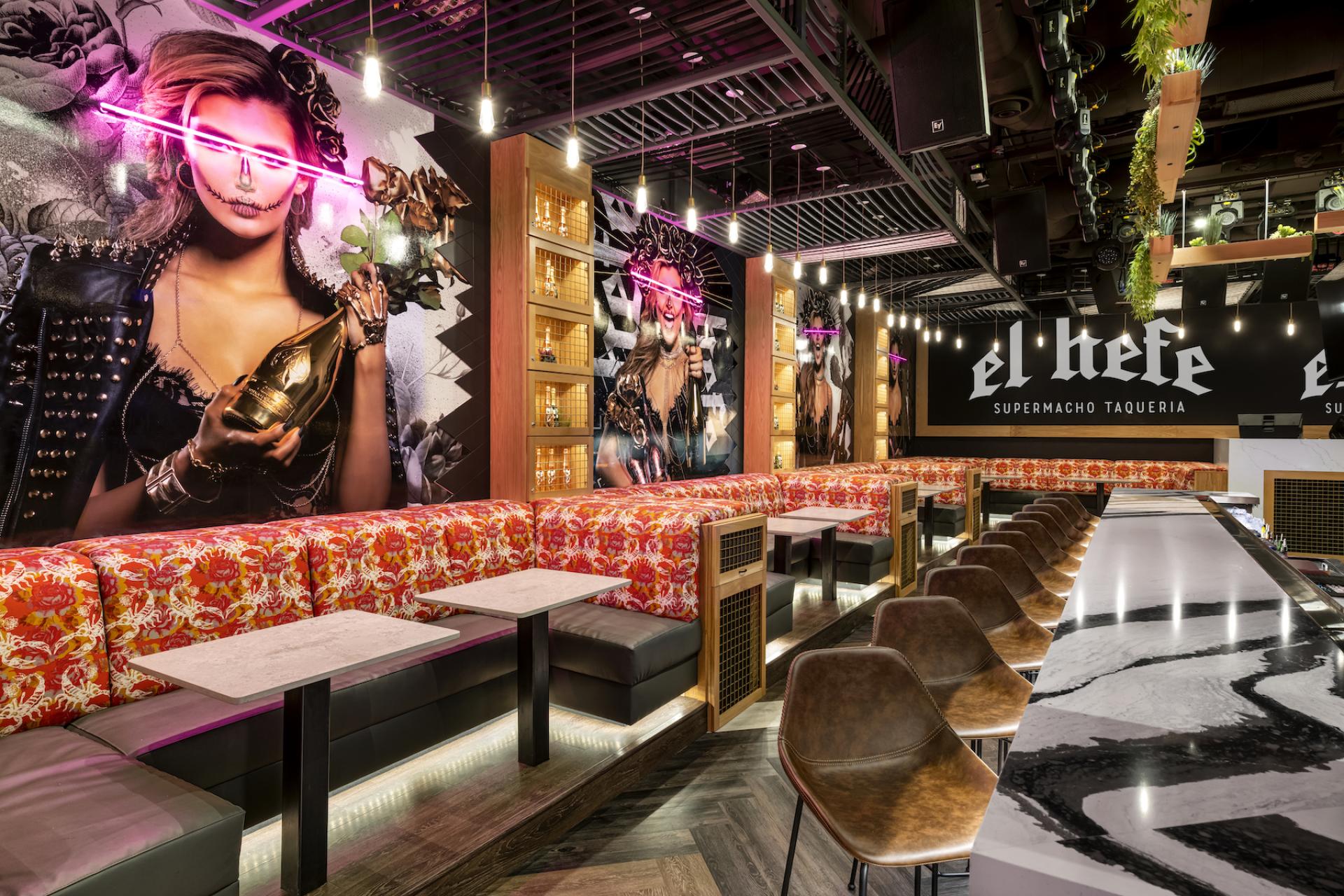 Vibrant interior of El Hefe Supermacho Taqueria featuring striking artwork, colorful seating, and stylish bar design.
