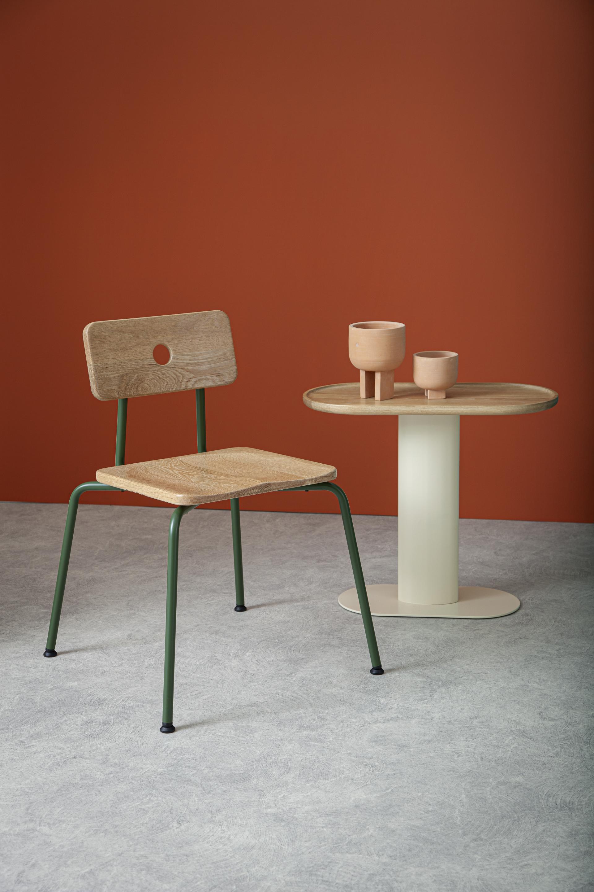 Modern wooden chair and minimalistic table with clay pots, showcased against a warm orange background for Liqui Contracts' collection.