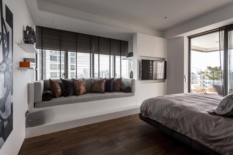 Modern bedroom design featuring a cozy window seat, sleek furnishings, and city views in Elliot James’ award-winning apartment.