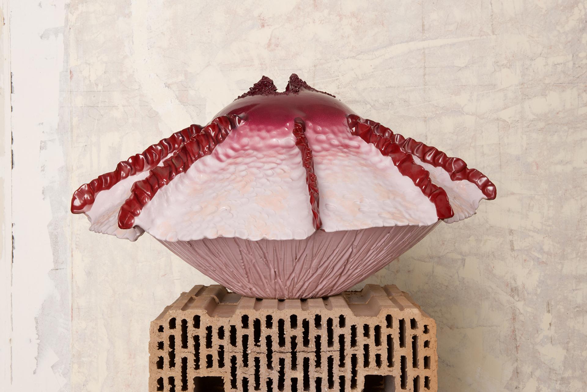 Colorful ceramic shell sculpture displayed on a textured block, part of Contemporary Cluster's exhibition in Rome.