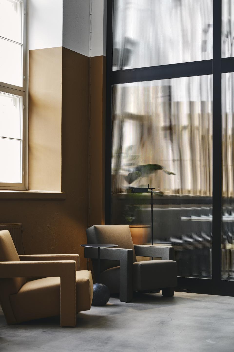 Stylish interior of a refurbished bread factory featuring modern armchairs and ambient lighting by Studio Joanna Laajisto.