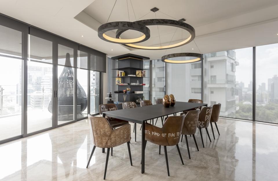 Modern dining area in an edgy Cuscaden One apartment showcasing stylish furniture and panoramic city views.
