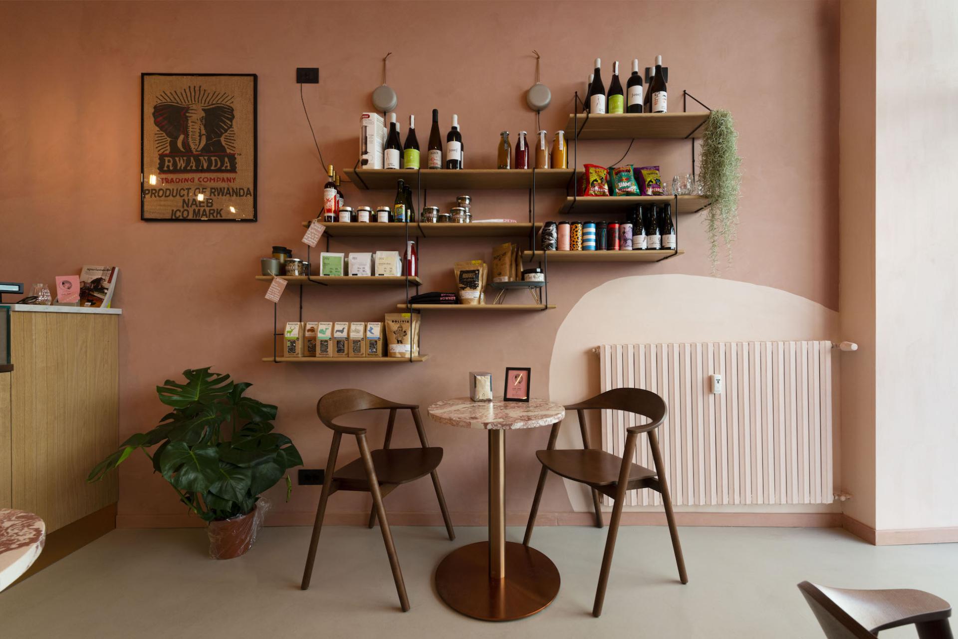 Cozy café interior featuring unique seating, minimalist decor, and shelves filled with local products and artful details.