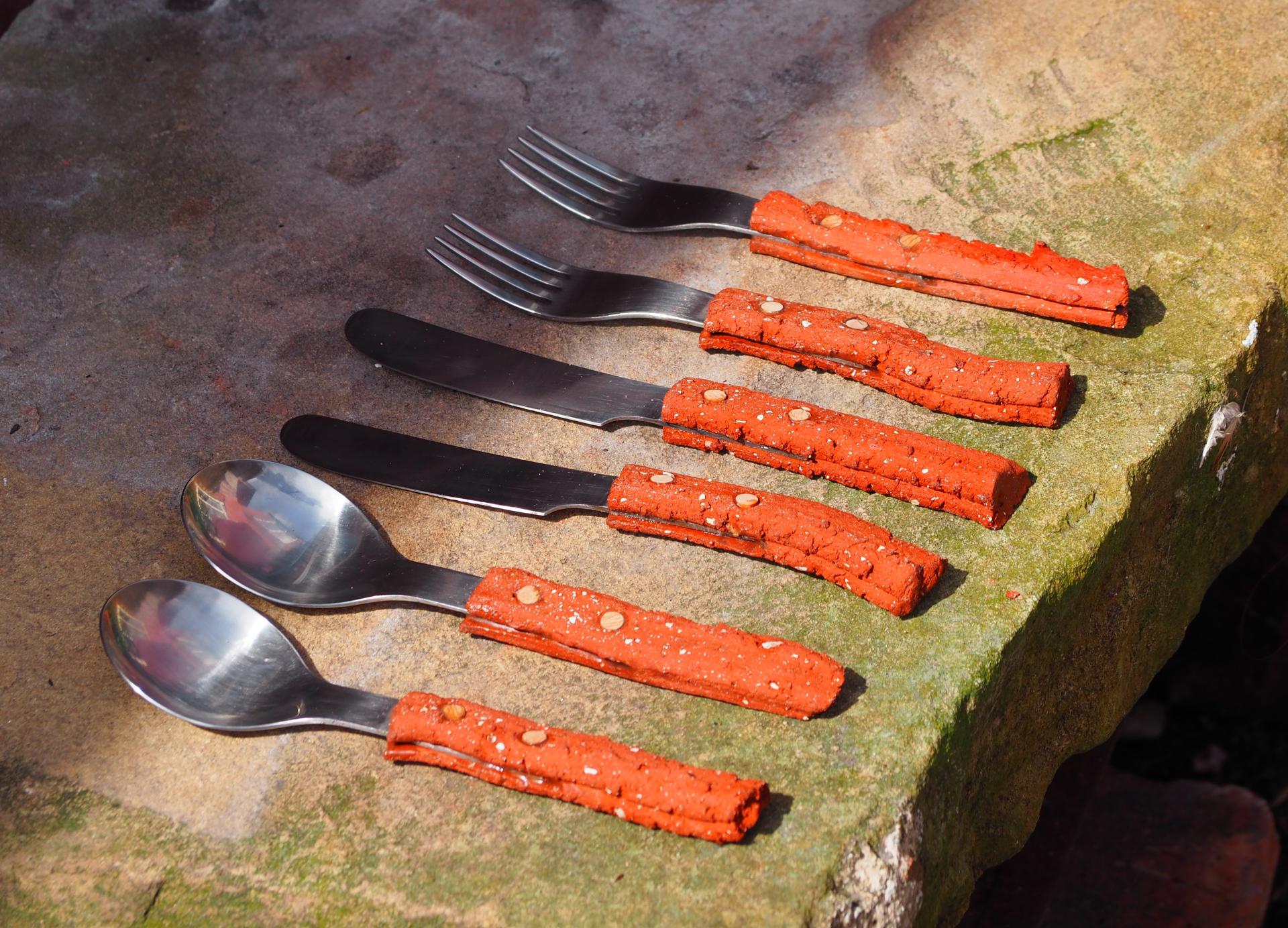 Colorful, eco-friendly cutlery with textured handles displayed on a stone surface, showcasing innovative design in sustainable dining.