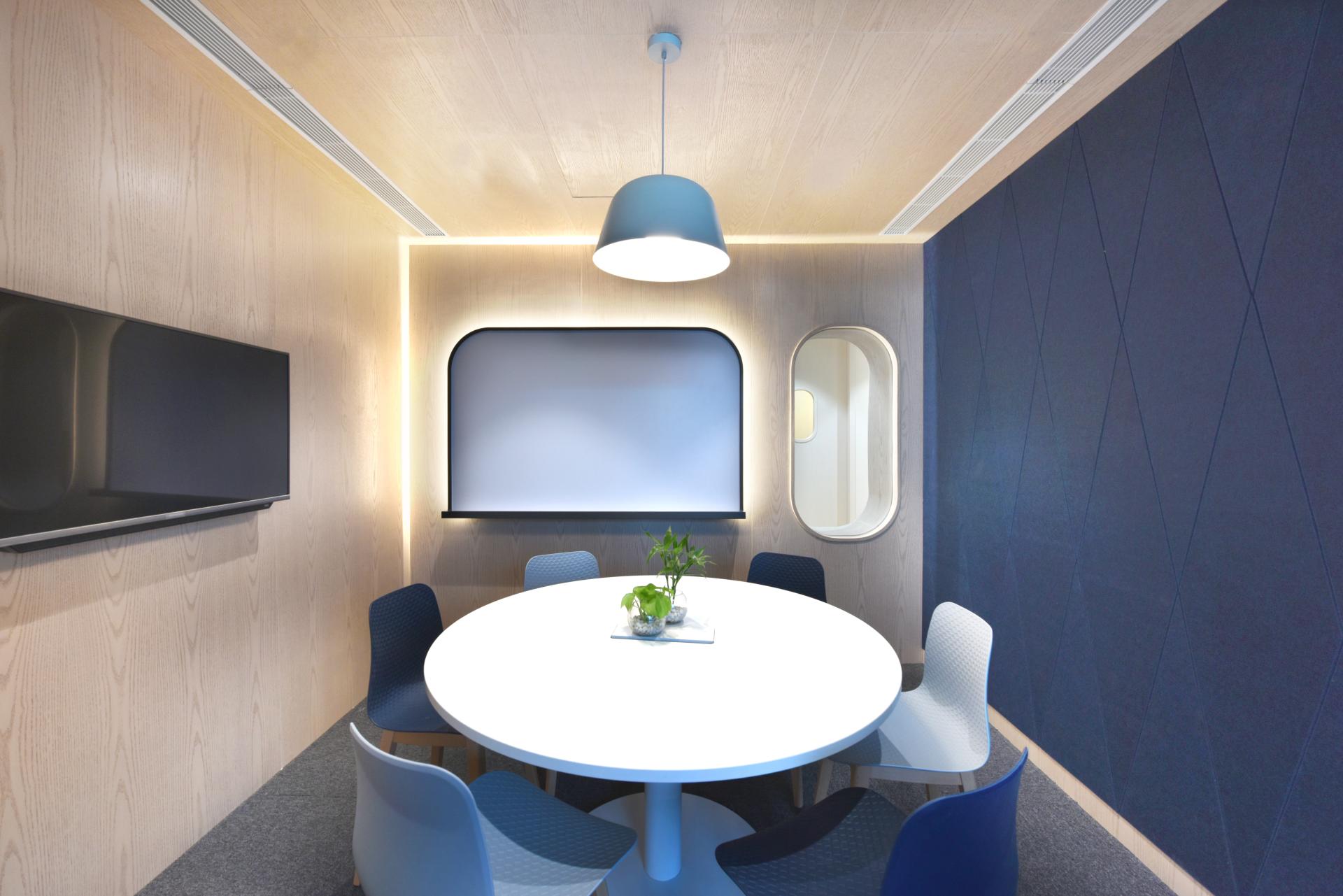 Modern conference room with a round table, stylish chairs, and sleek wall-mounted display, designed for travel technology meetings.