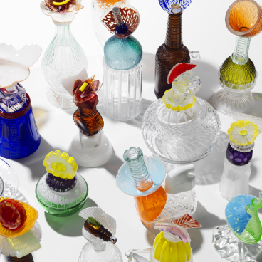 Colorful glass sculptures arranged artistically, showcasing creativity and innovation by UK-based experimental artists in the exhibition.