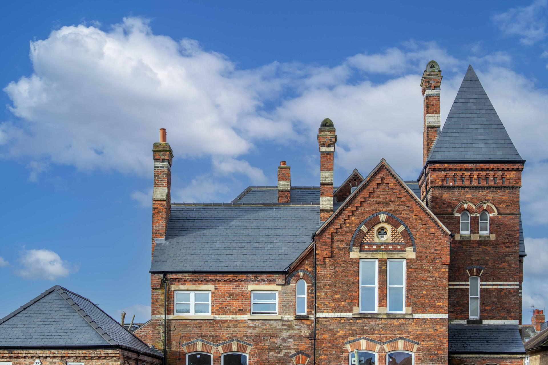 Victorian Gothic architecture of Heworth House featuring CUPA R12 Excellence slate roof against a clear blue sky.