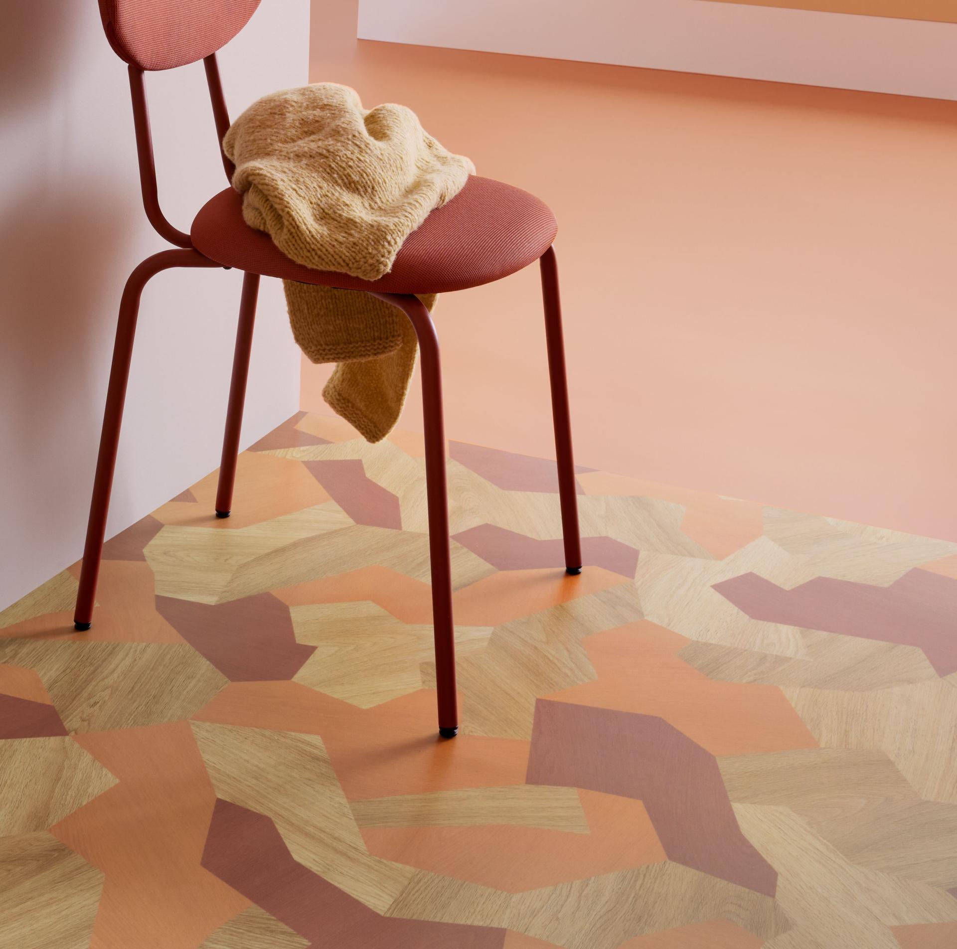 Vibrant Modul’up flooring with wood and stone patterns, complemented by a modern chair and cozy throw.
