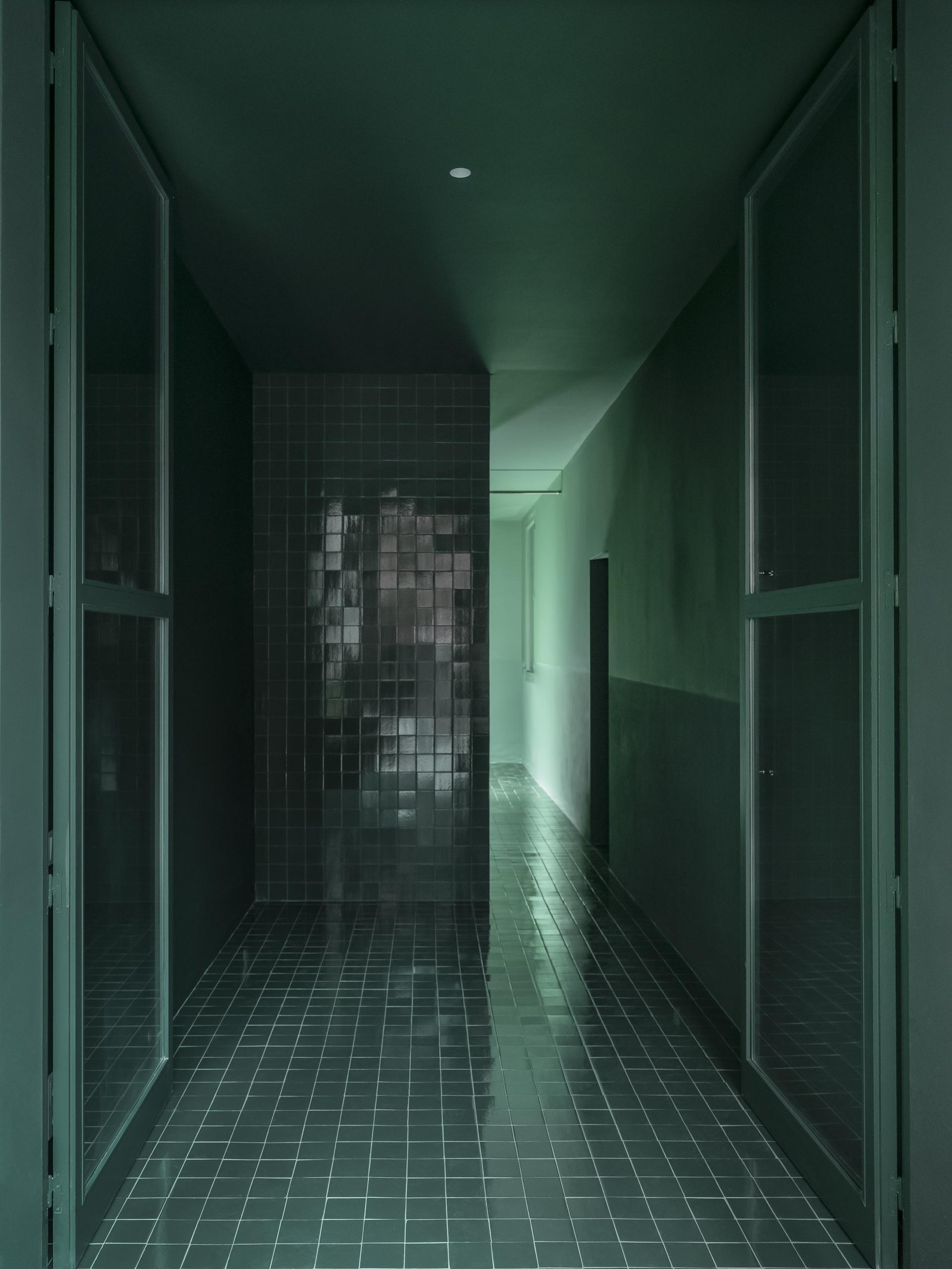 Modern corridor featuring innovative ceramic tile flooring and walls in shades of green, showcasing Spanish design creativity.