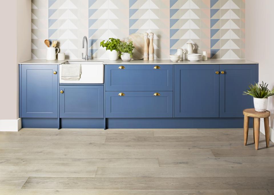Stylish kitchen featuring blue cabinetry, a farmhouse sink, and light wood flooring from Domus' new Pergo flooring collection.
