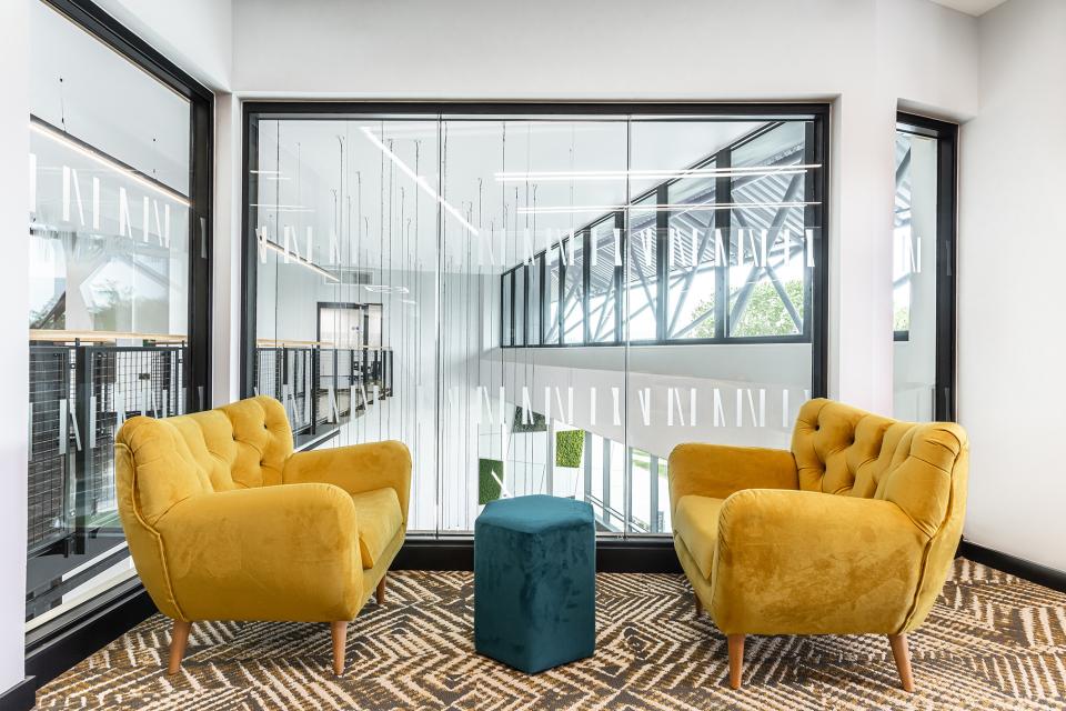 Stylish yellow armchairs with a teal ottoman in a bright, modern flexible workspace at The Bee House, Milton Park.