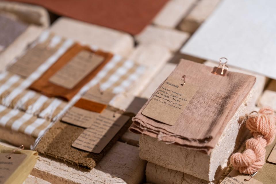 Exhibition display featuring various biomaterials and textiles with informational tags at Material Source Studio.