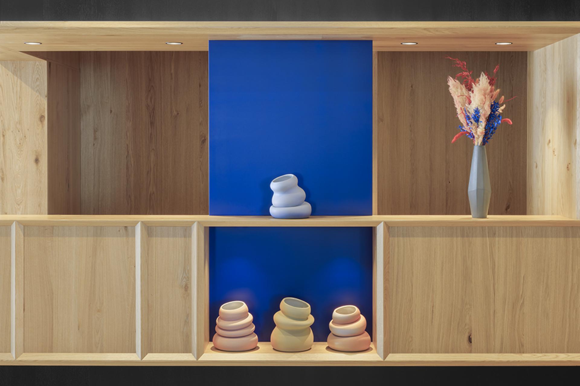 Elegant wooden shelving showcases modern pottery and colorful floral decor, reflecting the alpine-inspired design of Icaro Hotel.