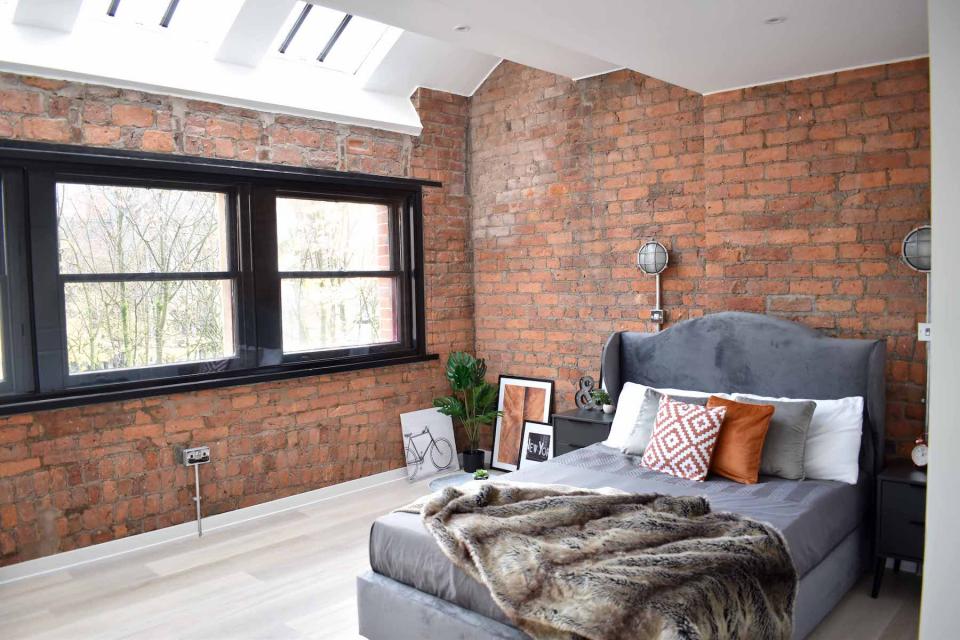 Stylish luxury apartment interior featuring exposed brick walls, modern furnishings, and large windows for natural light.