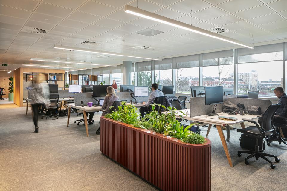 Modern office space at PZ Cussons headquarters, featuring collaborative workstations and indoor greenery for a sustainable atmosphere.