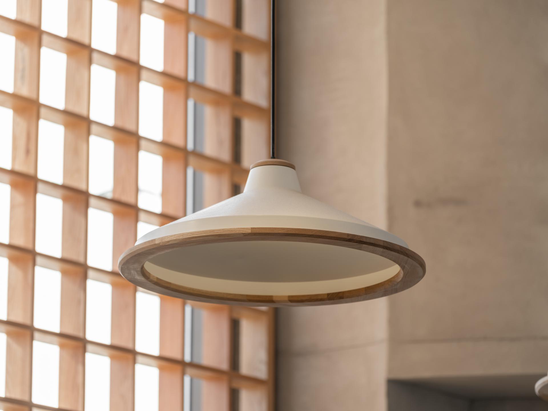 Stylish overhead lamp with wooden accents, complementing the Japandi aesthetic in Brew92's coffee shop interior design.