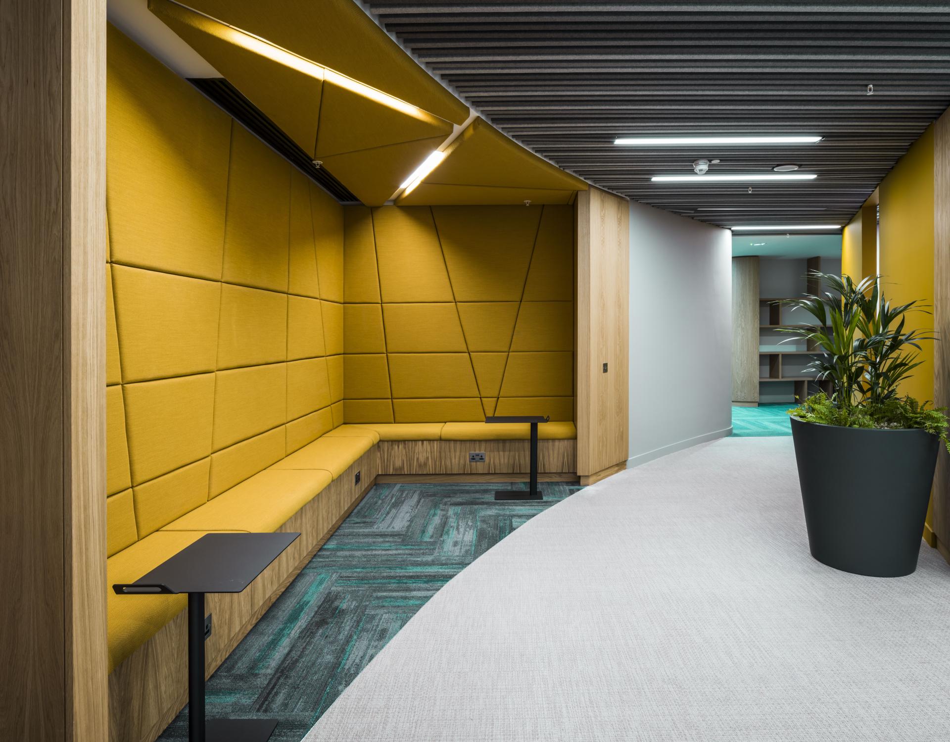 Contemporary office interior featuring yellow acoustic panels, cozy seating, and greenery, designed for WELL certification in Scotland.