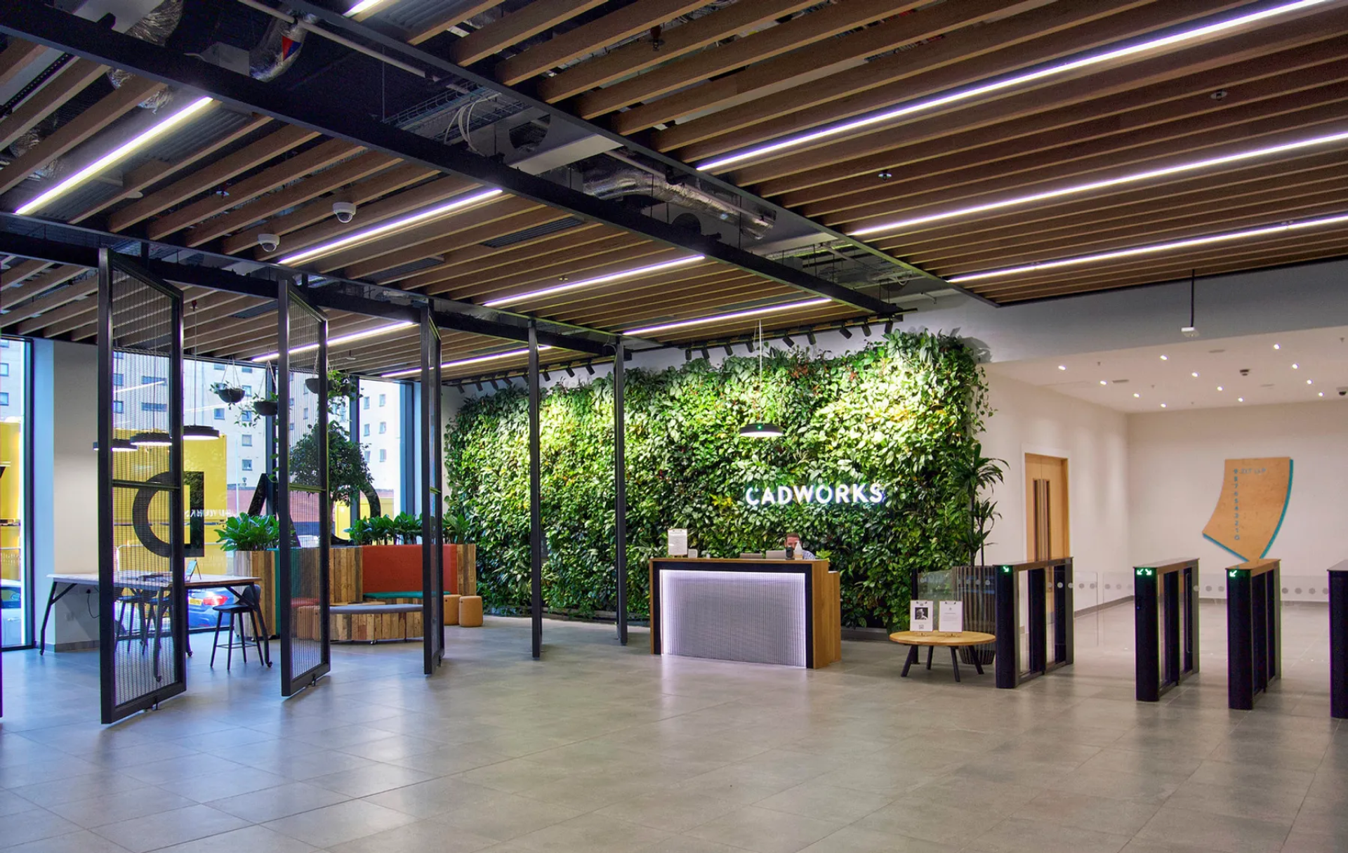 Modern office interior featuring a vibrant green wall, reception desk, and biophilic design elements.