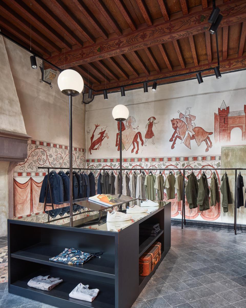 Contemporary COEF clothing shop interior featuring historical murals, stylish apparel displays, and modern lighting in Utrecht.