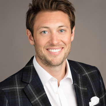 Rollie Attard, COO of Panaz, smiles confidently in a stylish plaid blazer, representing heritage and innovation in the hospitality industry.