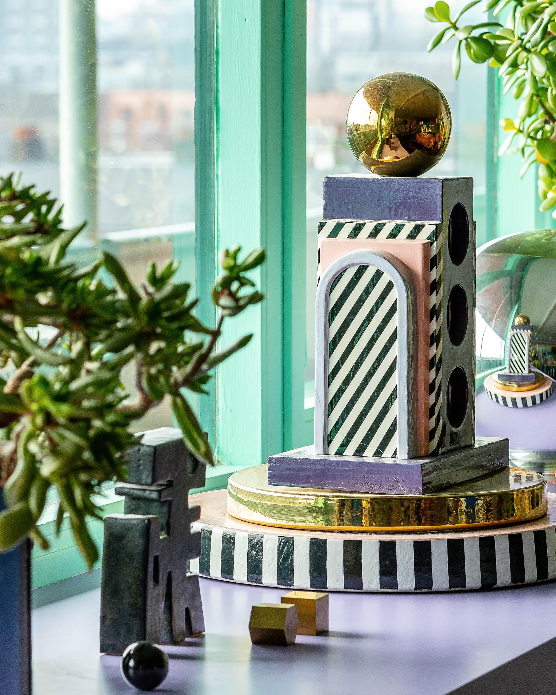 Colorful geometric sculptures and plants adorn Camille Walala's studio, showcasing her vibrant artistic style and creative expression.