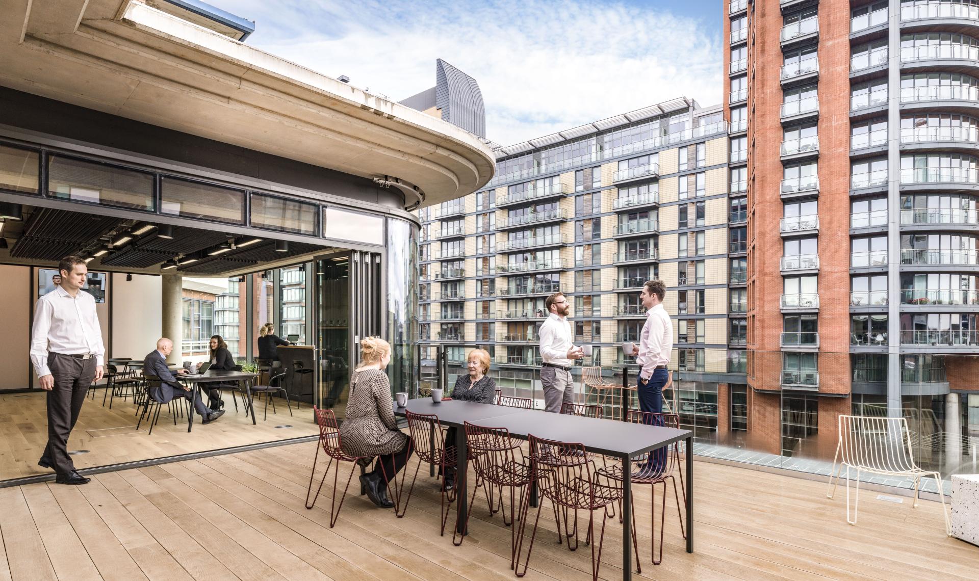 Modern workspace at Riverside House with professionals collaborating on a terrace, showcasing innovative design by SpaceInvader.