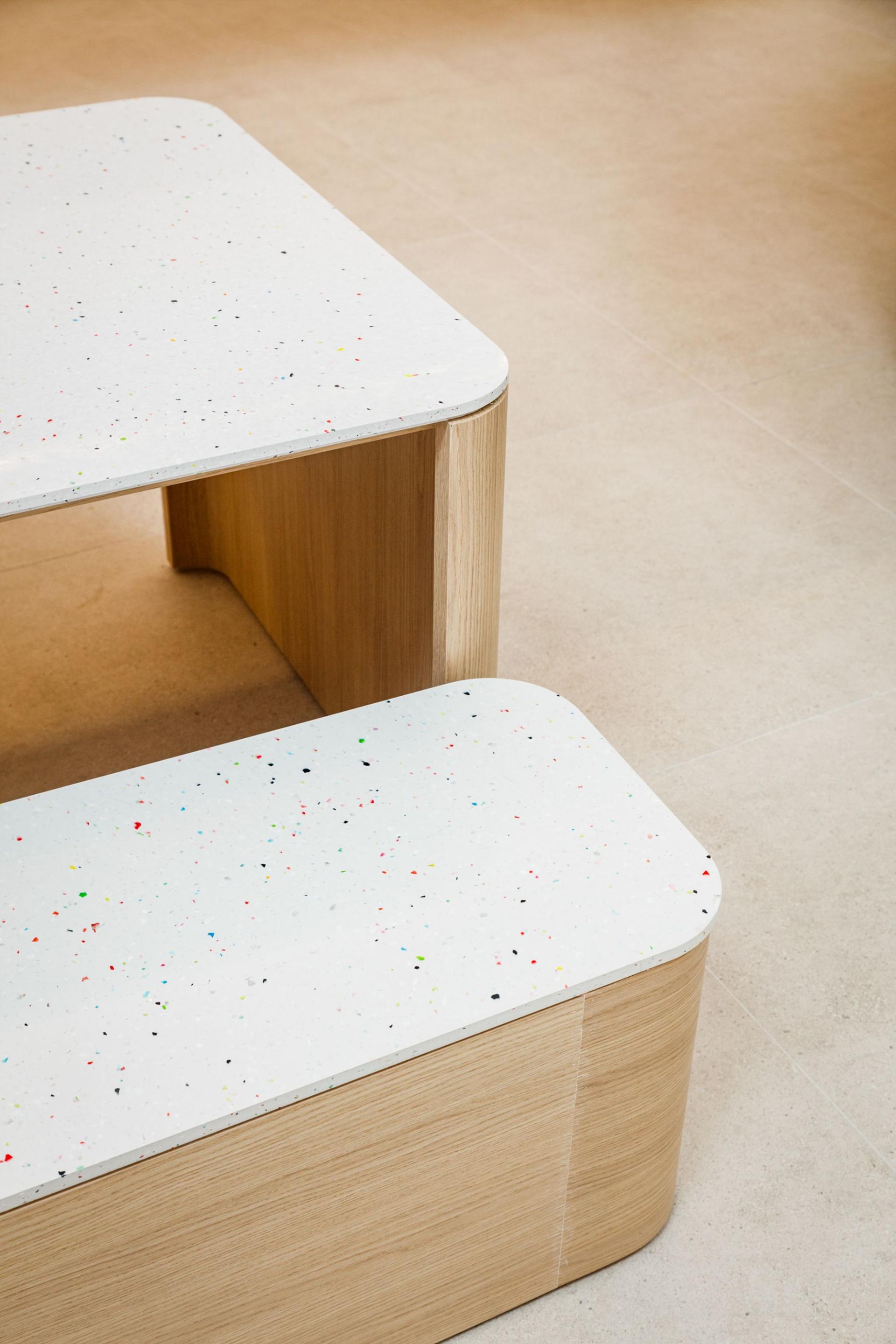 Modern wooden furniture with colorful speckled surfaces, showcasing sustainable design innovations from CDUK and The Good Plastic Company.