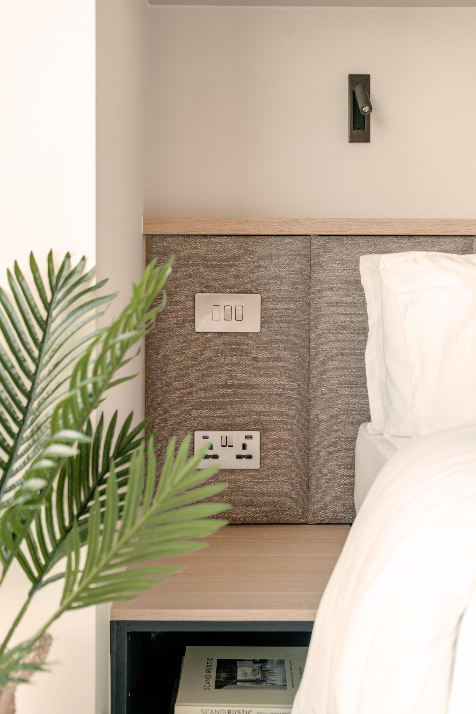 Modern co-living bedroom features stylish lighting, power outlets, and plants, showcasing Ekho Studio's design in The Apiary project.