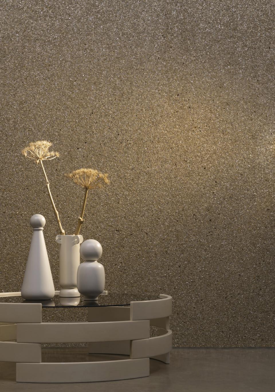 Stylish white vases and decorative elements on a modern tabletop against a textured wallcovering in neutral tones.