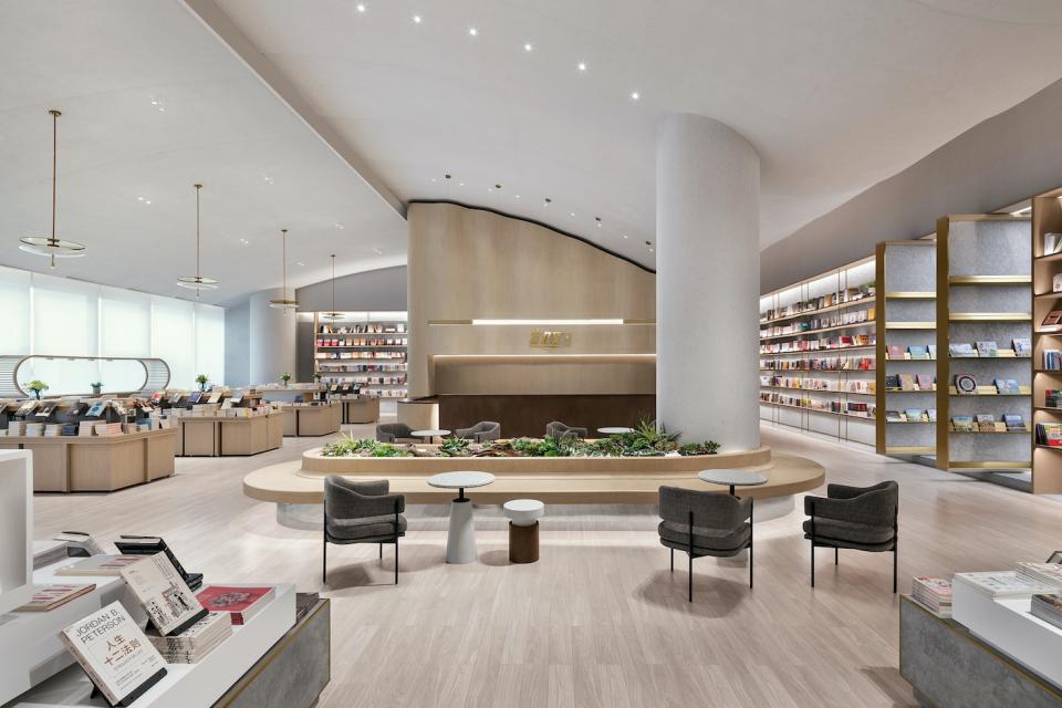 Modern book shop interior featuring elegant design, bookshelves, reading areas, and a landscaped central seating arrangement.
