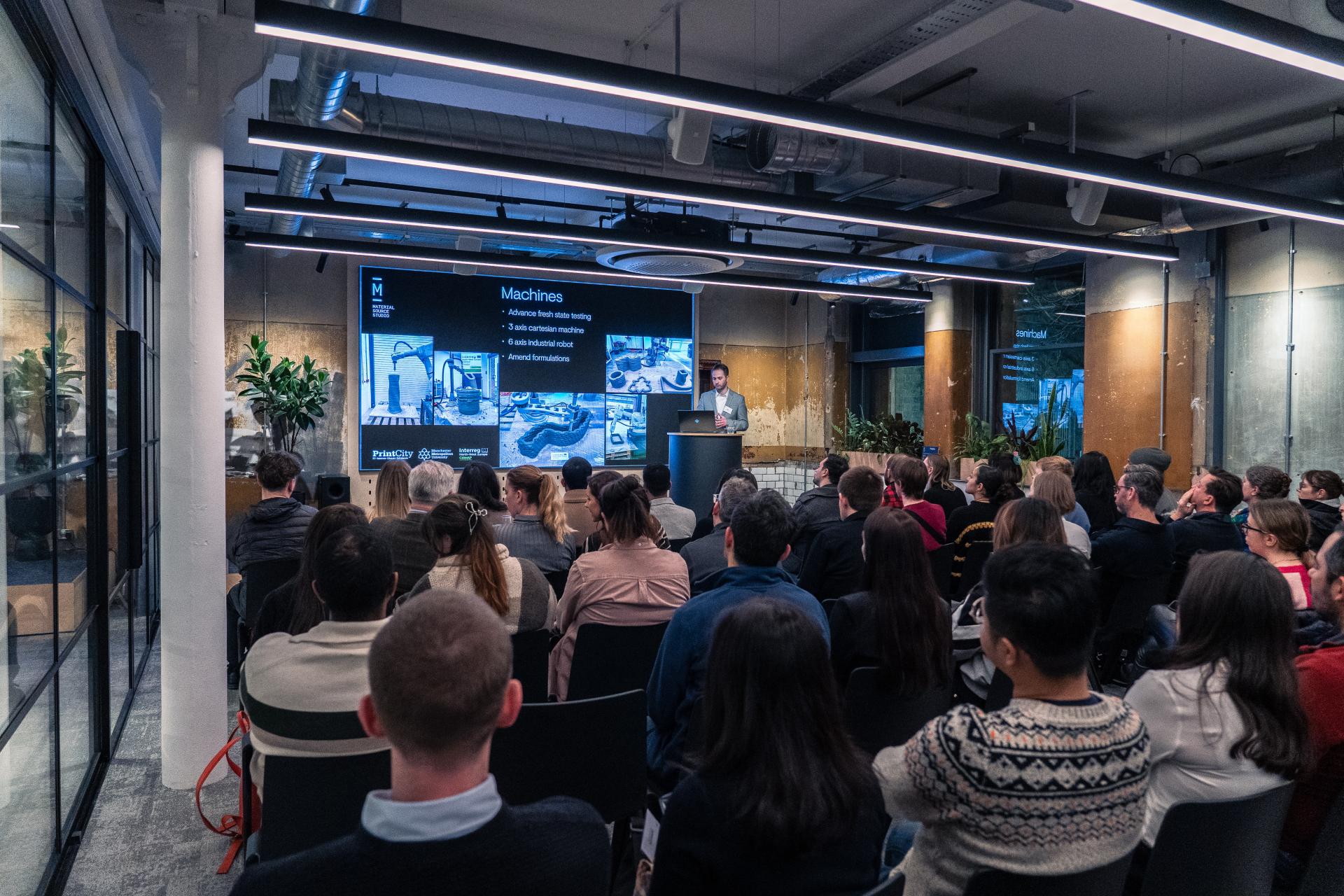 Nick Hurst presents sustainable 3D printing technologies at a Full Circle Concrete exhibition, with an engaged audience.
