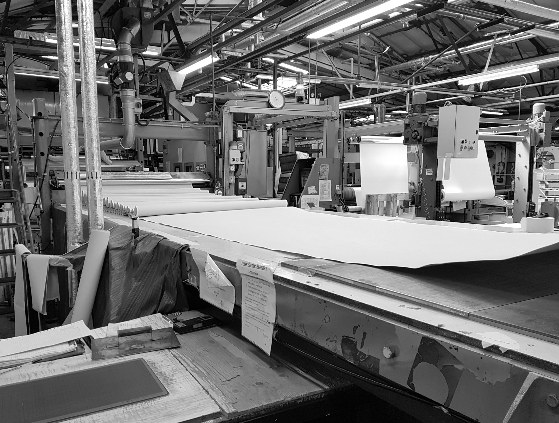 Production machinery inside Muraspec's Kent factory, showcasing large rolls of material being processed for wall coverings.