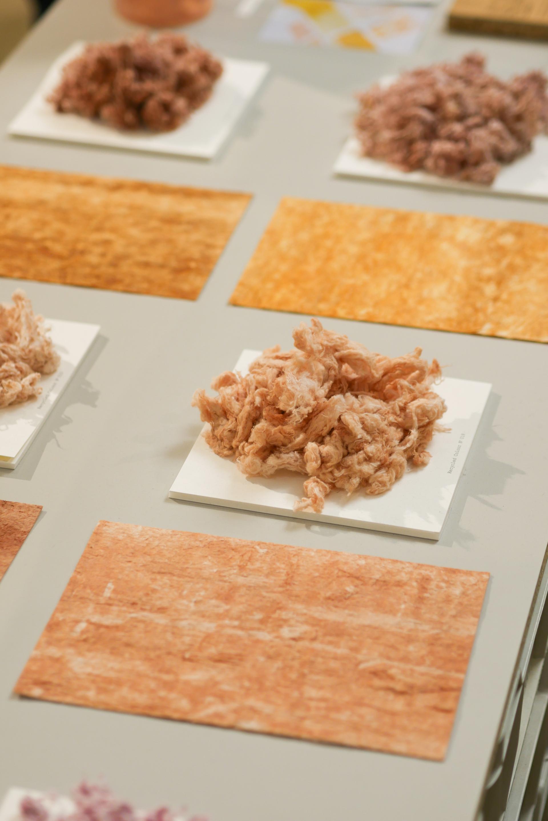Textured materials in varying warm colors displayed at a design event, highlighting innovative design trends for 2023.