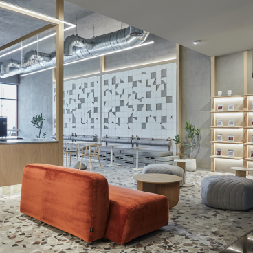 Minimalist coffee shop interior with raw accents, featuring modern seating and a stylish pastry display in Dubai.