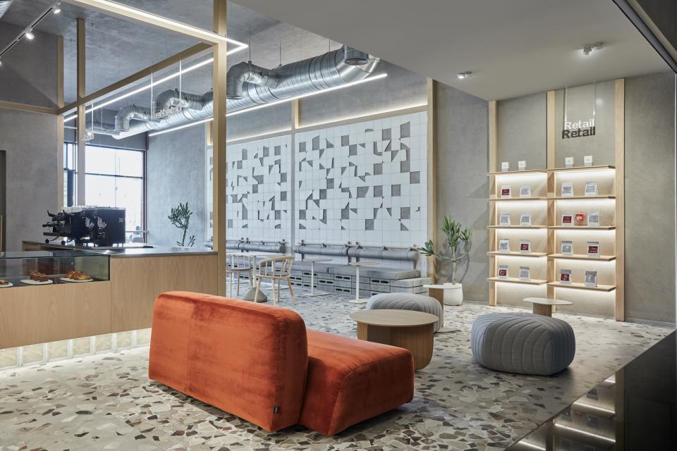 Minimalist coffee shop interior with raw accents, featuring modern seating and a stylish pastry display in Dubai.