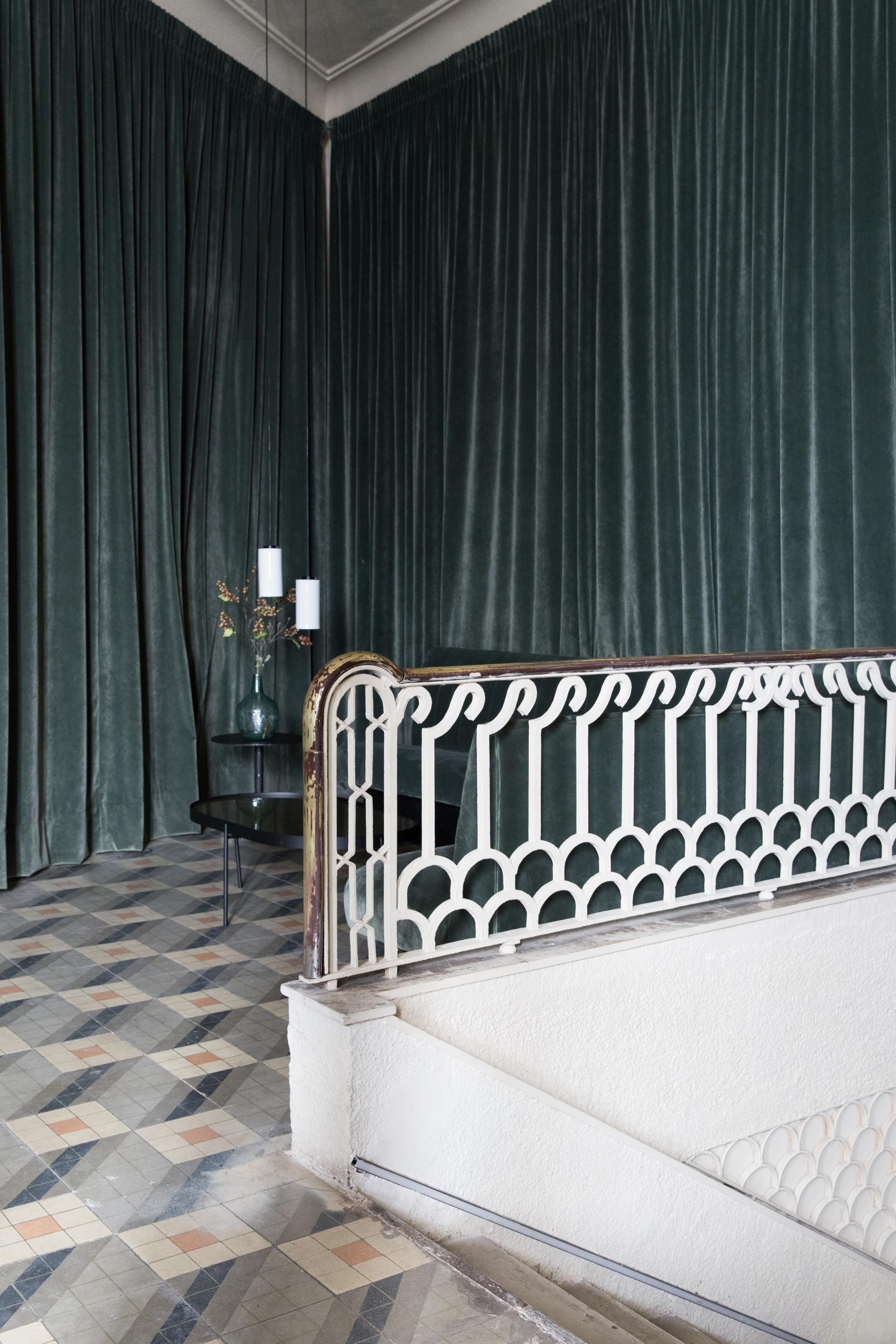 Luxurious interior featuring velvet curtains, intricate tile flooring, and an elegant railing, reflecting a vintage Americana aesthetic.