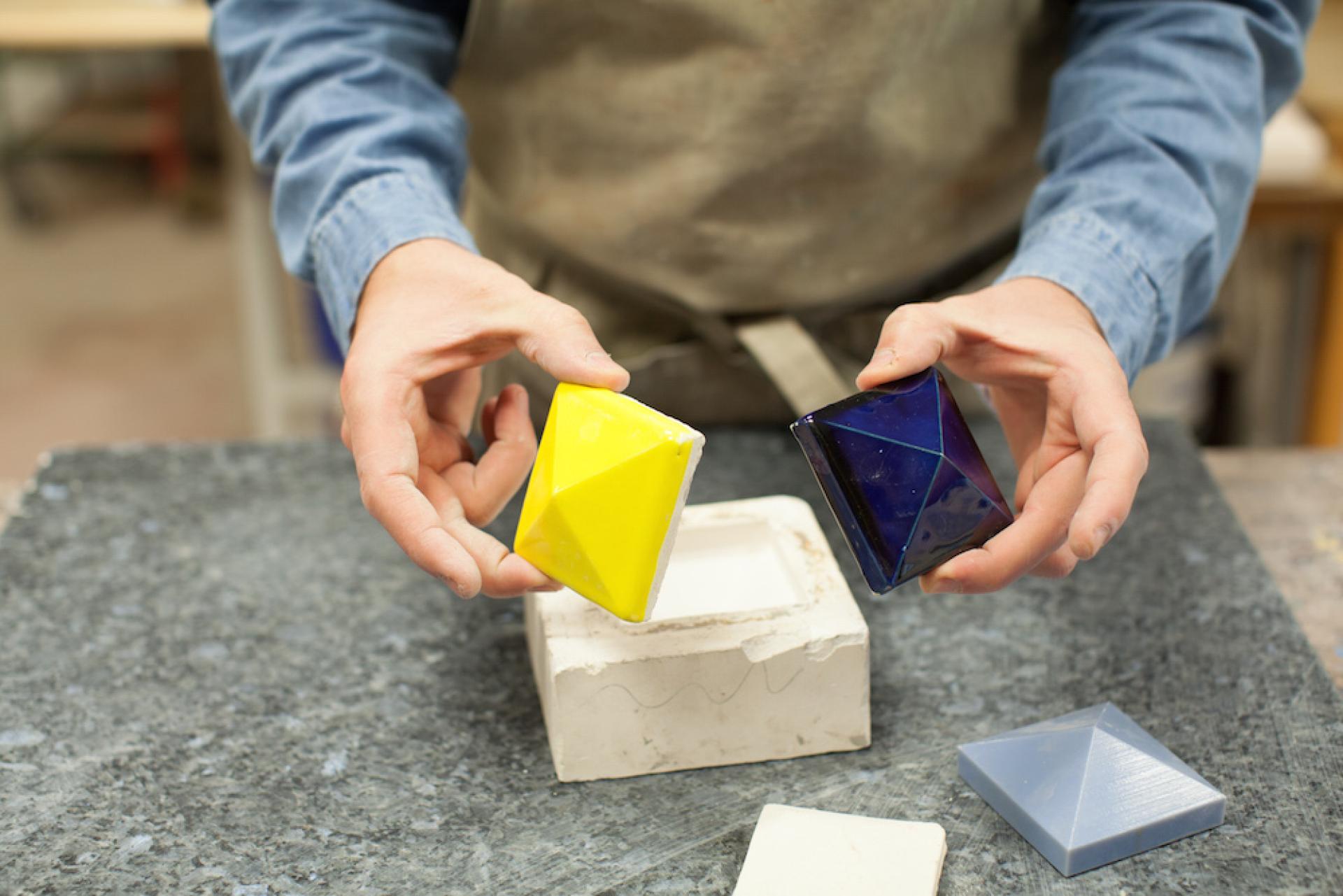Ceramic artist Matthew Raw demonstrating colorful geometric clay pieces in his workshop, exploring artistic possibilities with clay.