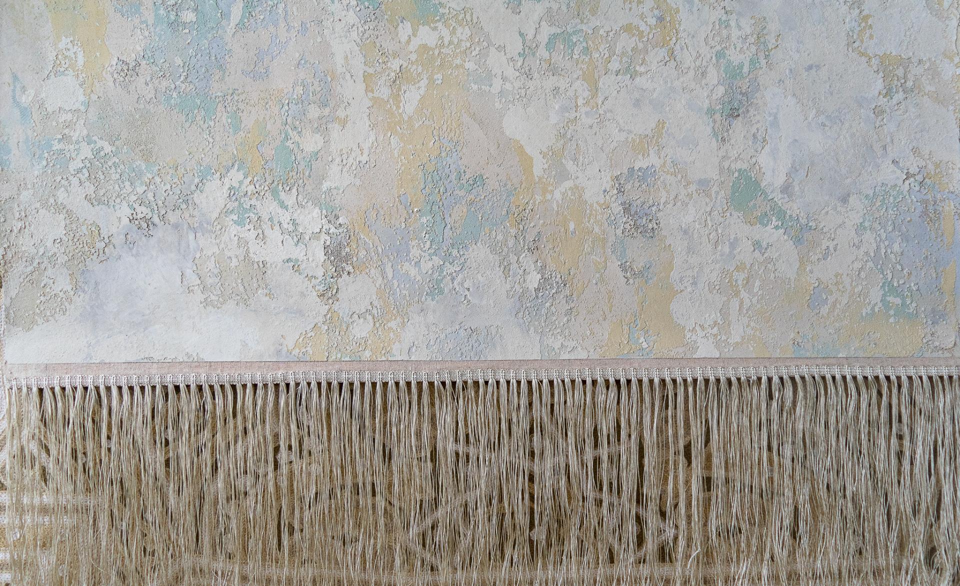 Artisan wall finish showcasing textured layers in soft pastel colors, complemented by a decorative fringe at the bottom.