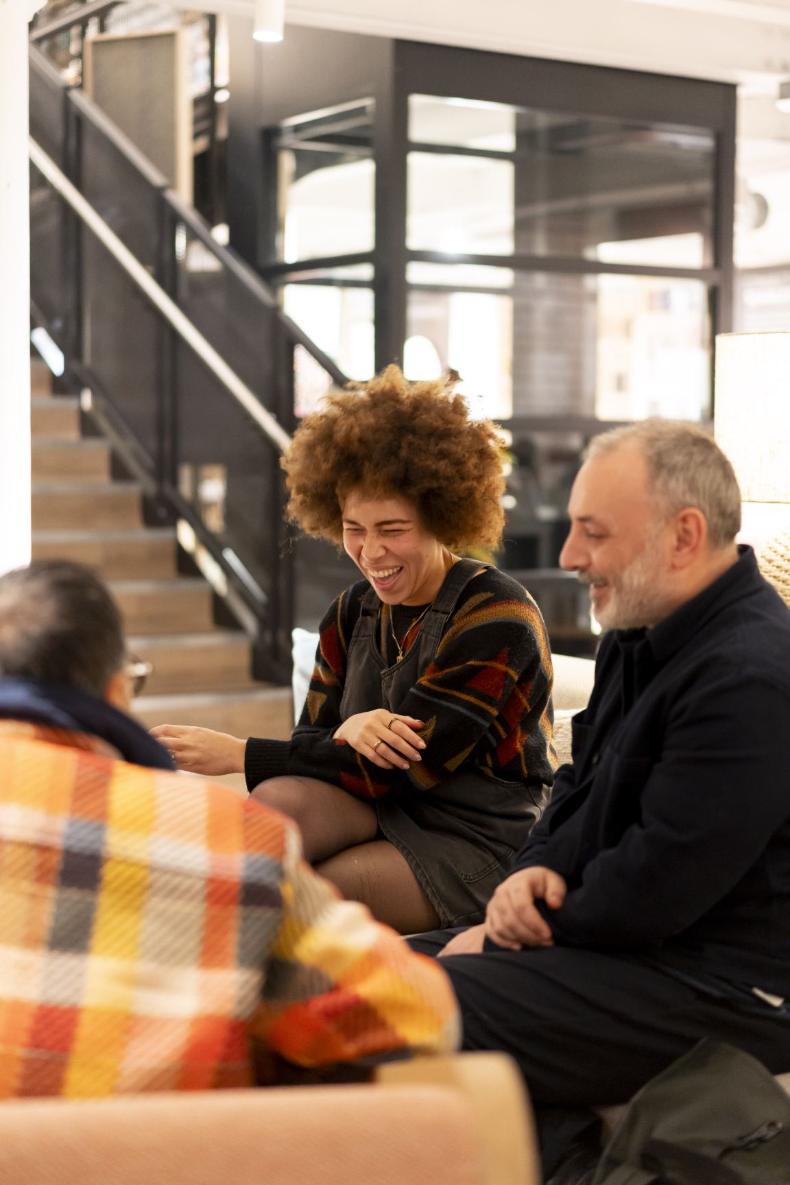 Three people engaged in joyful conversation at Material Source Studio Manchester, celebrating three years of creativity and community.