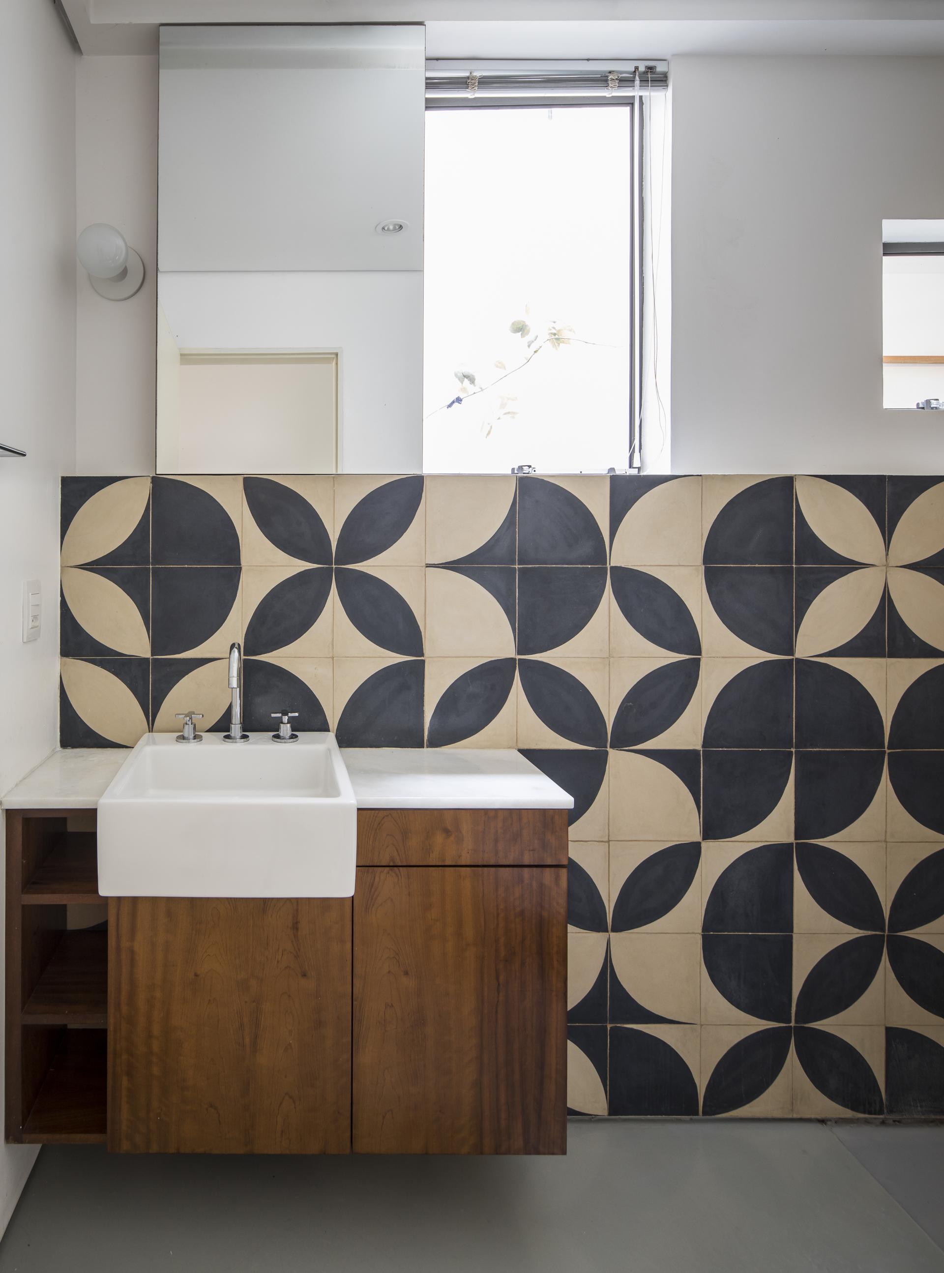 Modern bathroom design featuring a vintage-inspired sink and geometric patterned tiles in a renovated São Paulo apartment.