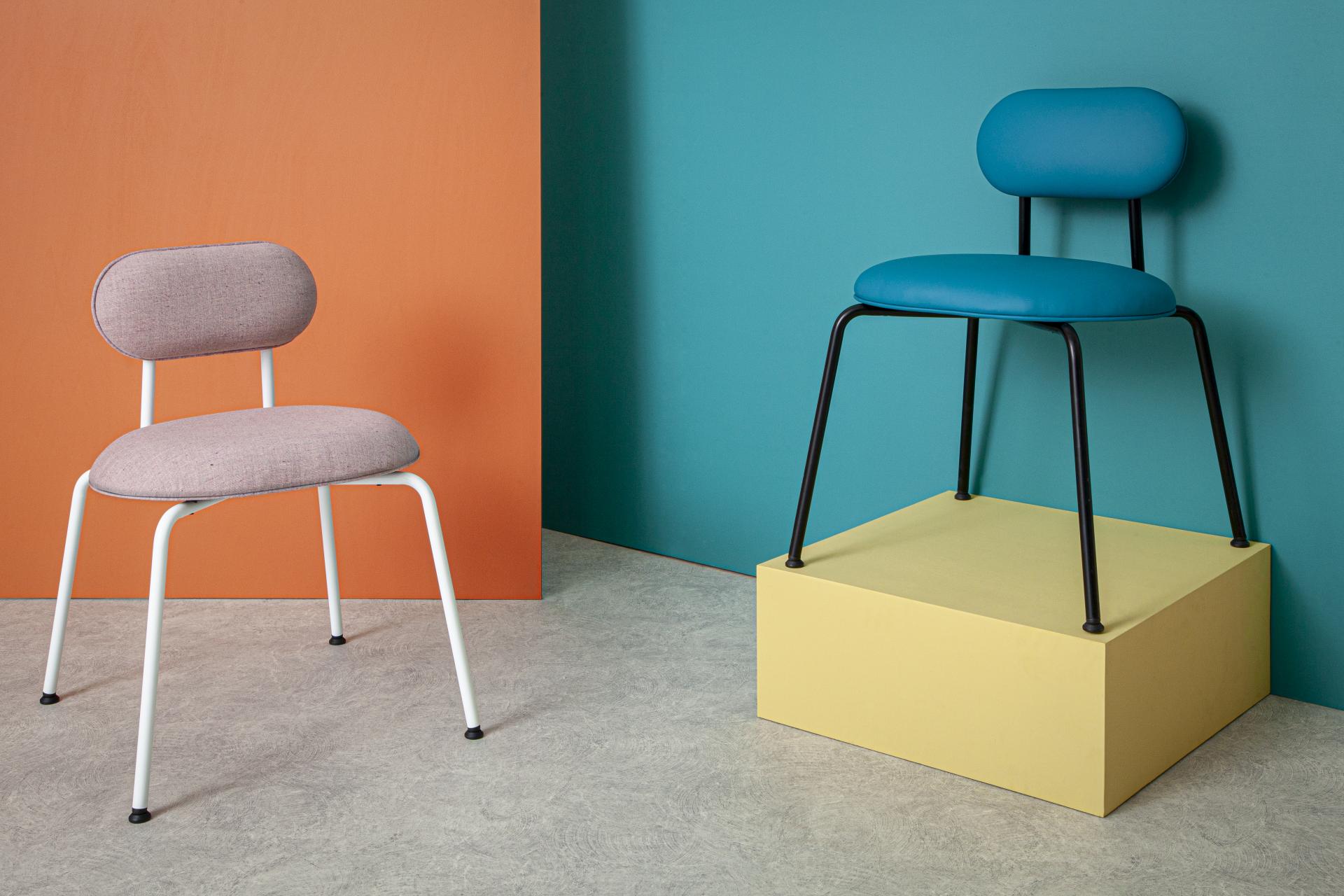 Two modern chairs in vibrant colors showcased against a backdrop of bold painted walls at Liqui Contracts' collection.